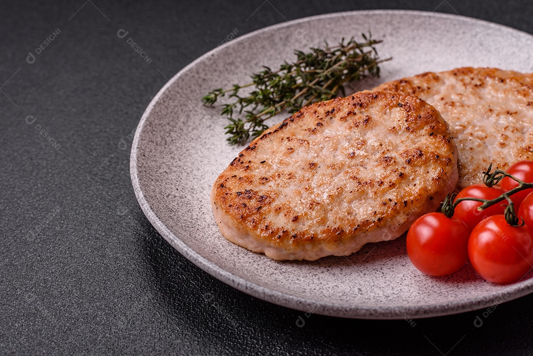 A imagem mostra chuletas de porco grelhadas, acompanhadas de ramos de tomilho e tomates cereja.