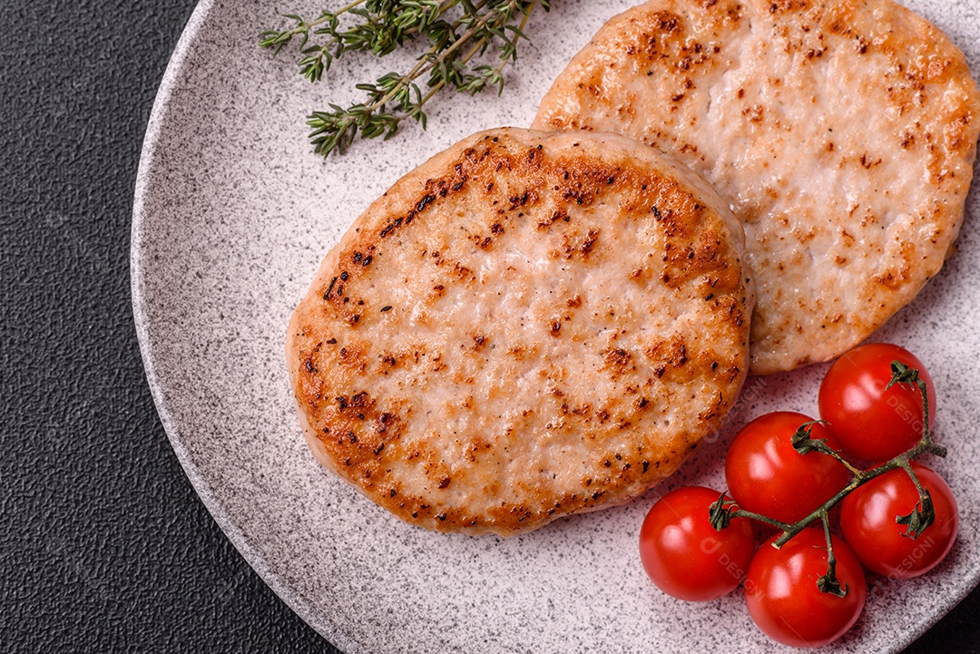 A imagem mostra chuletas de porco grelhadas, acompanhadas de ramos de tomilho e tomates cereja.