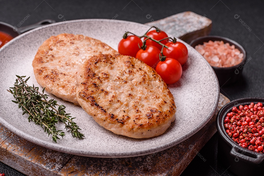 A imagem mostra chuletas de porco grelhadas, acompanhadas de ramos de tomilho e tomates cereja.
