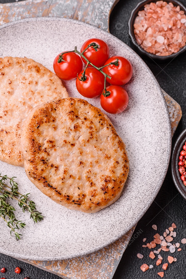 A imagem mostra chuletas de porco grelhadas, acompanhadas de ramos de tomilho e tomates cereja.