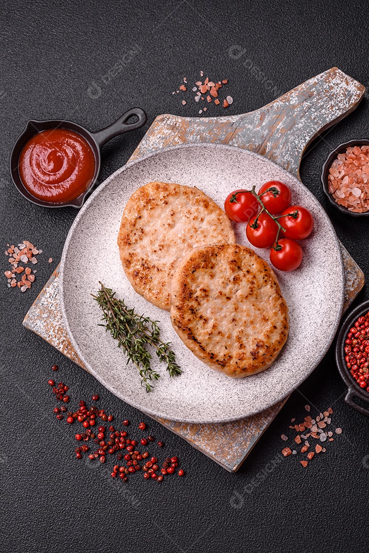 A imagem mostra chuletas de porco grelhadas, acompanhadas de ramos de tomilho e tomates cereja.