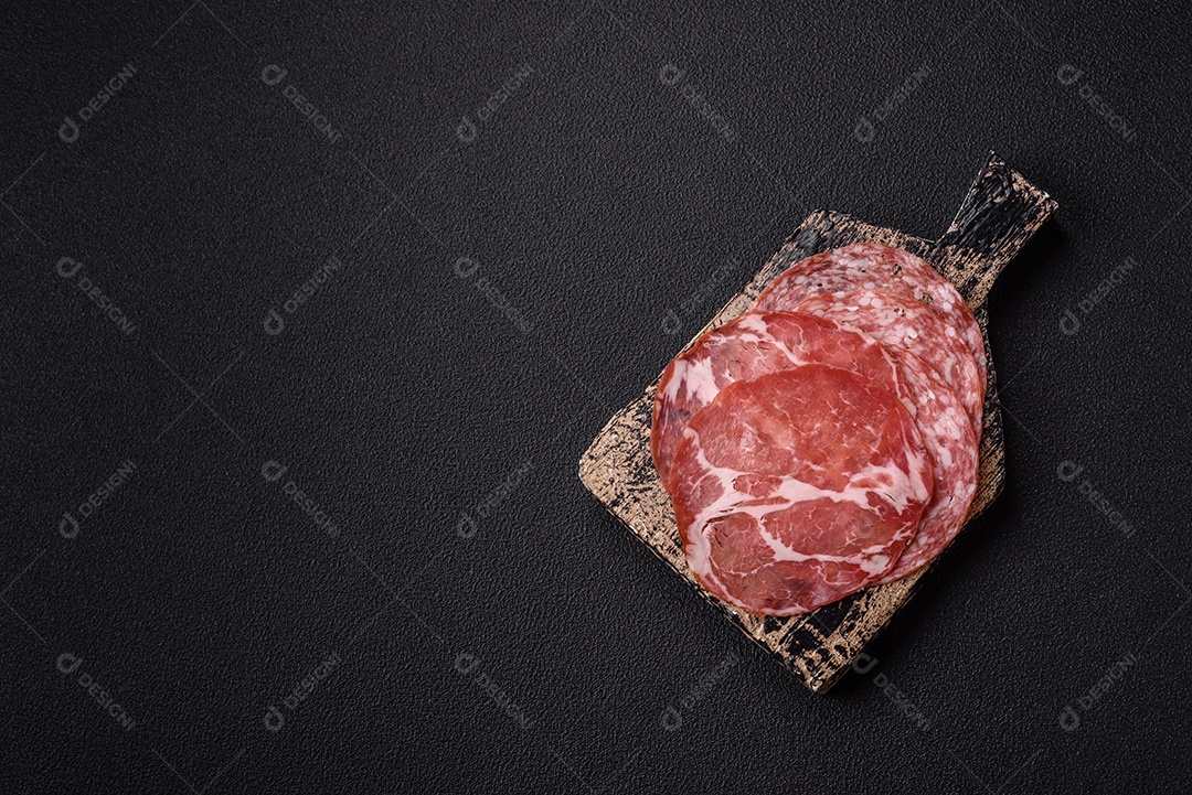 A imagem mostra um prato de embutidos, com destaque para fatias de salame e presunto cru, acompanhados de tomates-cereja e pimenta rosa