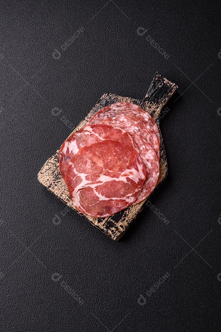 A imagem mostra um prato de embutidos, com destaque para fatias de salame e presunto cru, acompanhados de tomates-cereja e pimenta rosa