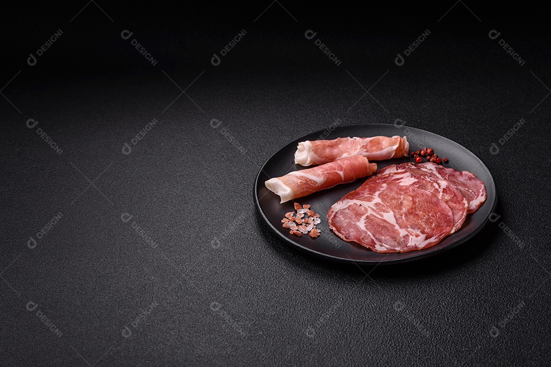 A imagem mostra um prato de embutidos, com destaque para fatias de salame e presunto cru, acompanhados de tomates-cereja e pimenta rosa