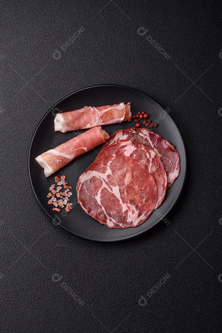 A imagem mostra um prato de embutidos, com destaque para fatias de salame e presunto cru, acompanhados de tomates-cereja e pimenta rosa