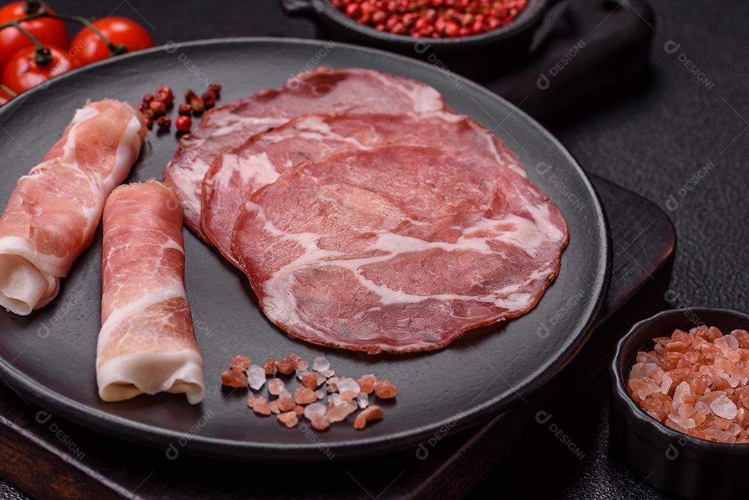 A imagem mostra um prato de embutidos, com destaque para fatias de salame e presunto cru, acompanhados de tomates-cereja e pimenta rosa