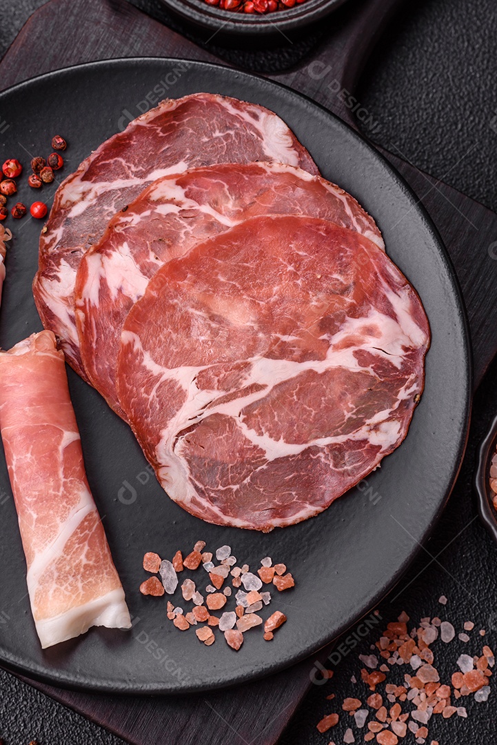 A imagem mostra um prato de embutidos, com destaque para fatias de salame e presunto cru, acompanhados de tomates-cereja e pimenta rosa