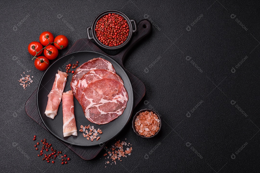 A imagem mostra um prato de embutidos, com destaque para fatias de salame e presunto cru, acompanhados de tomates-cereja e pimenta rosa