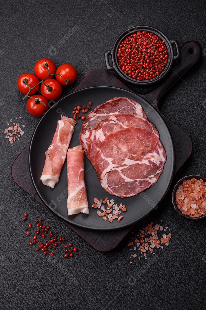 A imagem mostra um prato de embutidos, com destaque para fatias de salame e presunto cru, acompanhados de tomates-cereja e pimenta rosa