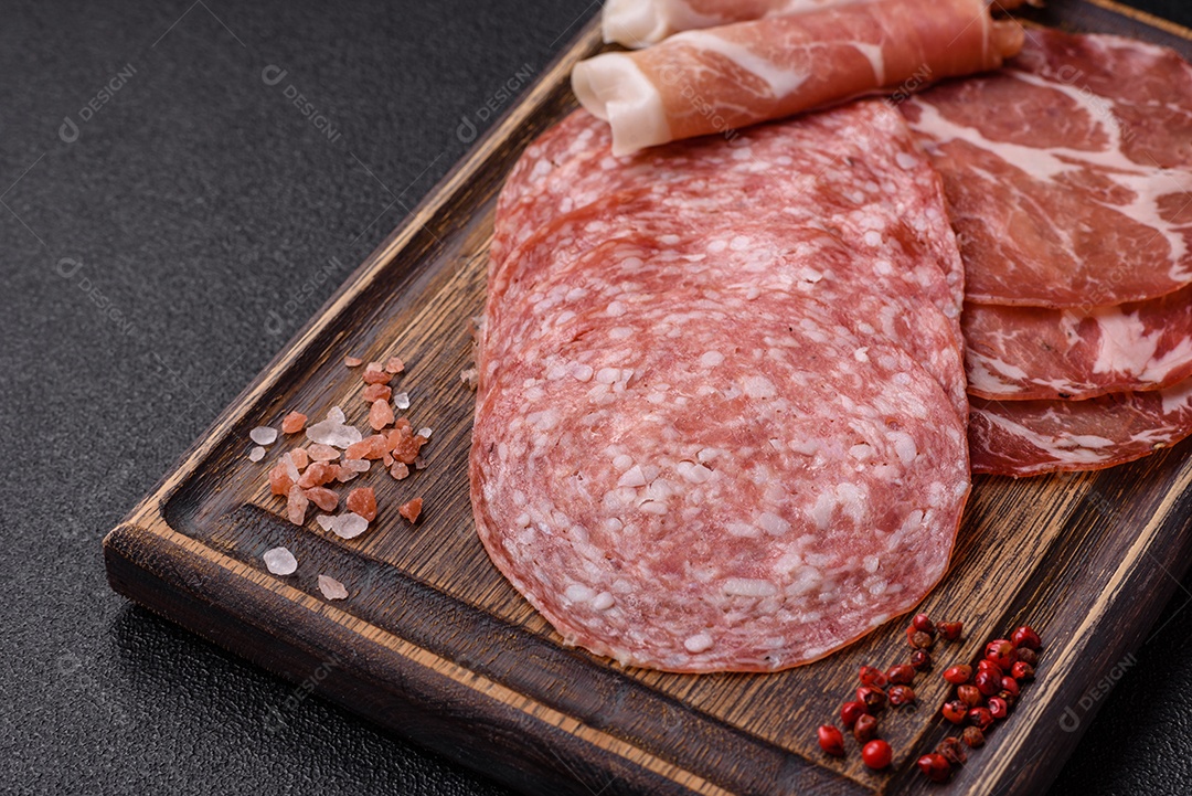 A imagem mostra um prato de embutidos, com destaque para fatias de salame e presunto cru, acompanhados de tomates-cereja e pimenta rosa