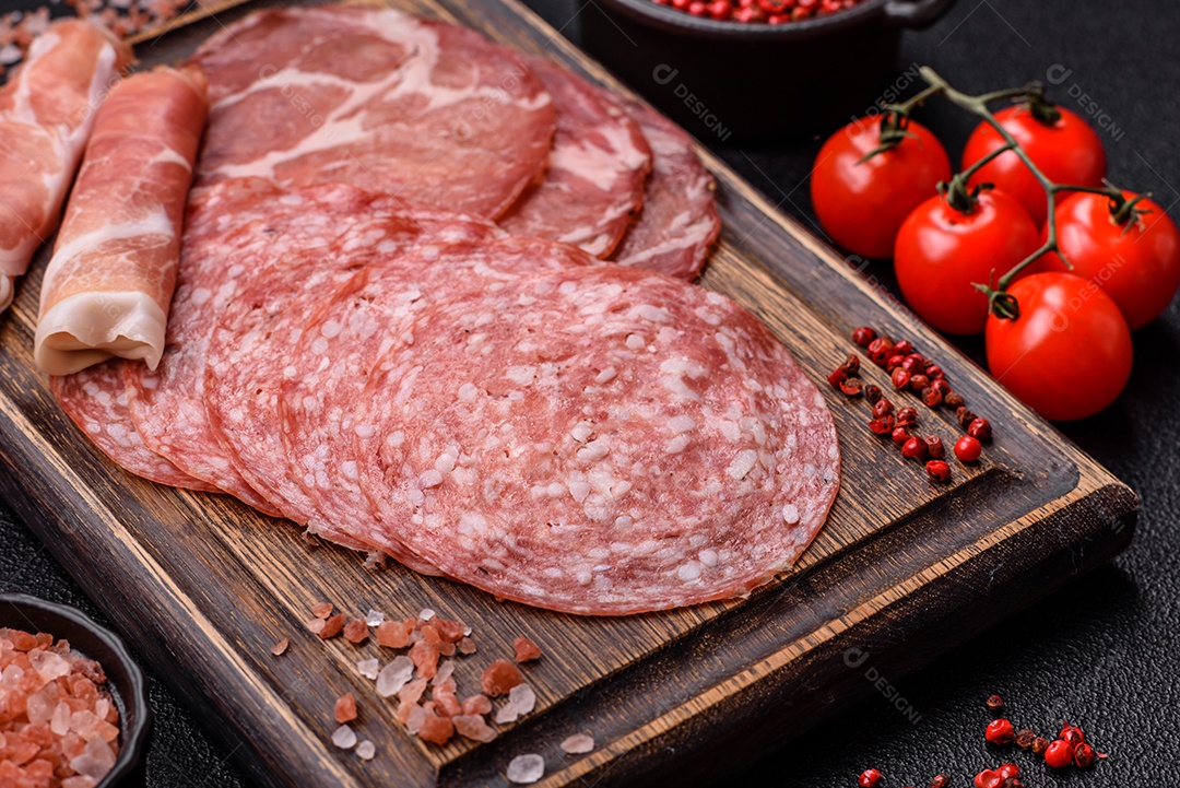 A imagem mostra um prato de embutidos, com destaque para fatias de salame e presunto cru, acompanhados de tomates-cereja e pimenta rosa