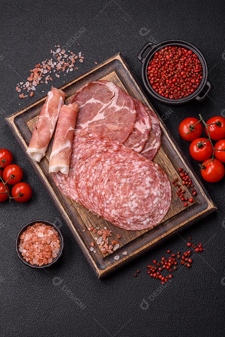 A imagem mostra um prato de embutidos, com destaque para fatias de salame e presunto cru, acompanhados de tomates-cereja e pimenta rosa