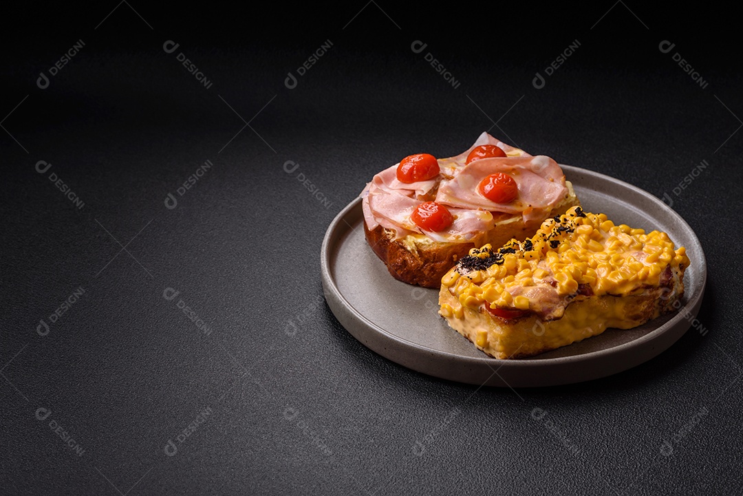A imagem mostra um sanduíche de brioche com presunto, queijo derretido e tomates cereja, polvilhado com sal e pimenta.
