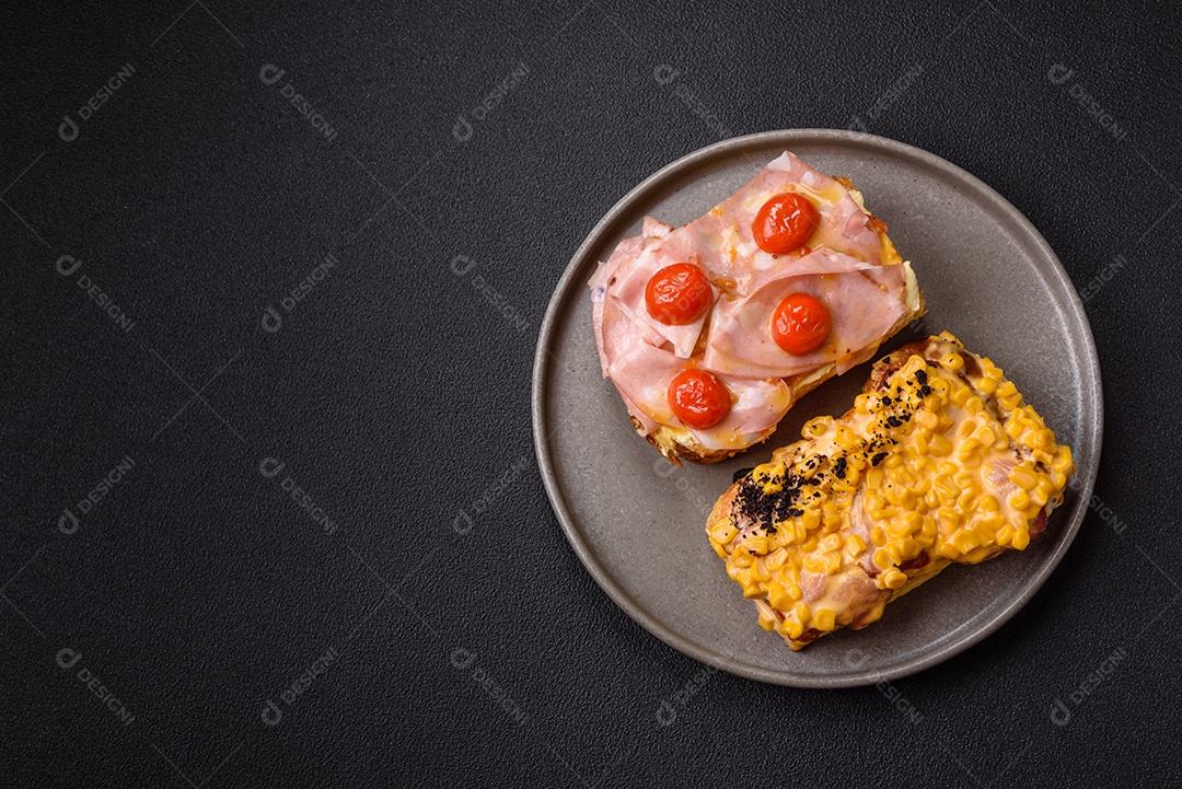A imagem mostra um sanduíche de brioche com presunto, queijo derretido e tomates cereja, polvilhado com sal e pimenta.