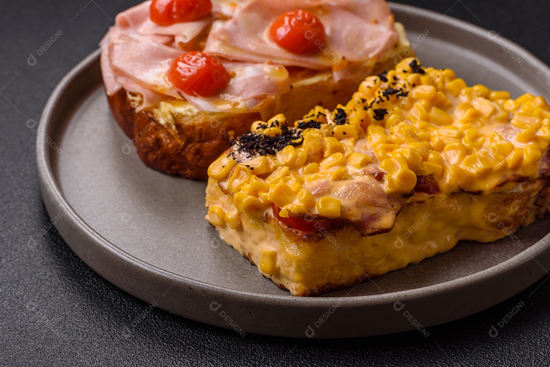 A imagem mostra um sanduíche de brioche com presunto, queijo derretido e tomates cereja, polvilhado com sal e pimenta.