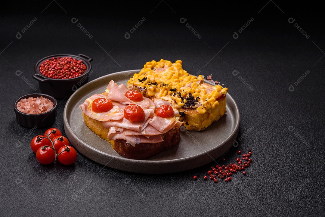 A imagem mostra um sanduíche de brioche com presunto, queijo derretido e tomates cereja, polvilhado com sal e pimenta.