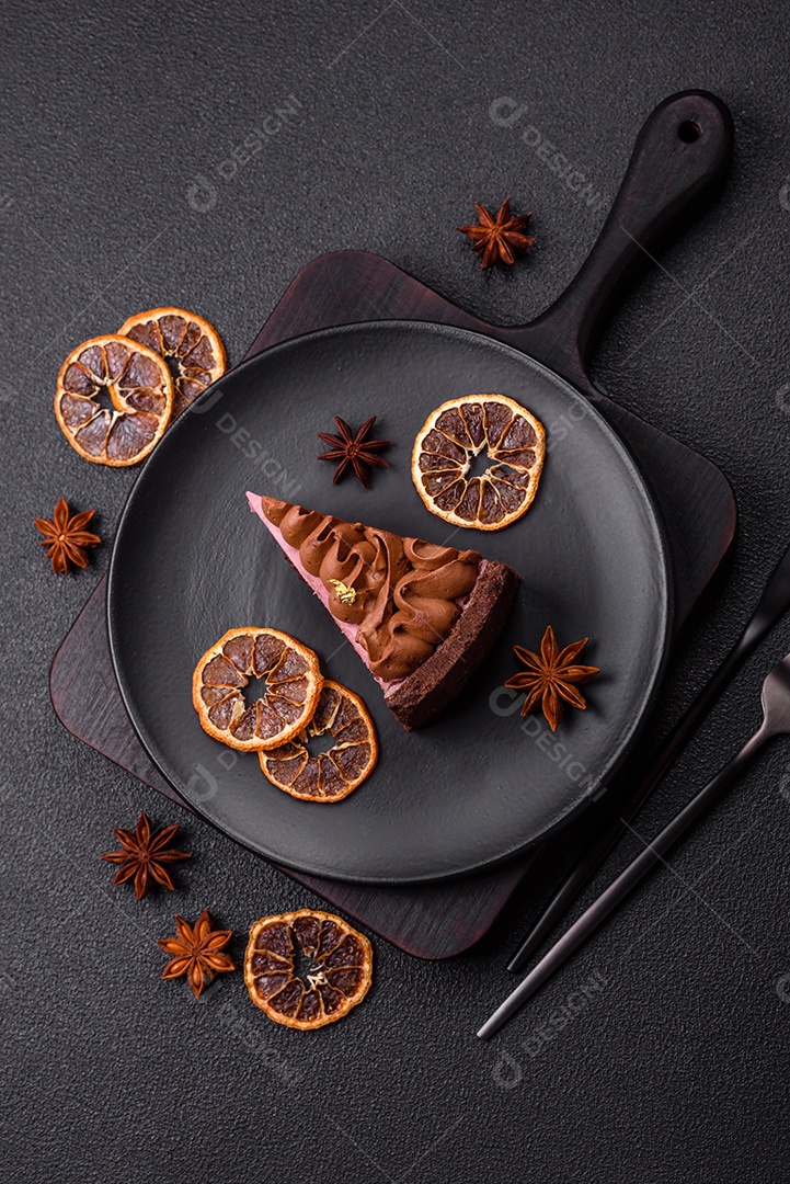 A imagem mostra uma fatia de bolo ou torta de chocolate, possivelmente com uma camada de recheio ou cobertura de cor diferente, decorada com rodelas de laranja