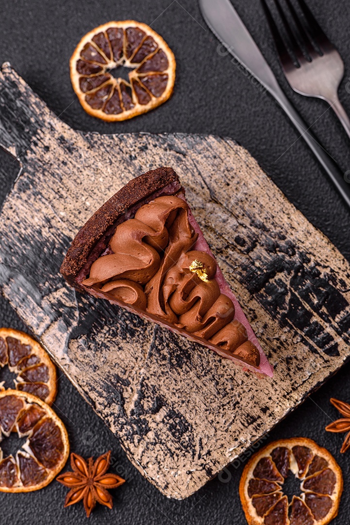 A imagem mostra uma fatia de bolo ou torta de chocolate, possivelmente com uma camada de recheio ou cobertura de cor diferente, decorada com rodelas de laranja