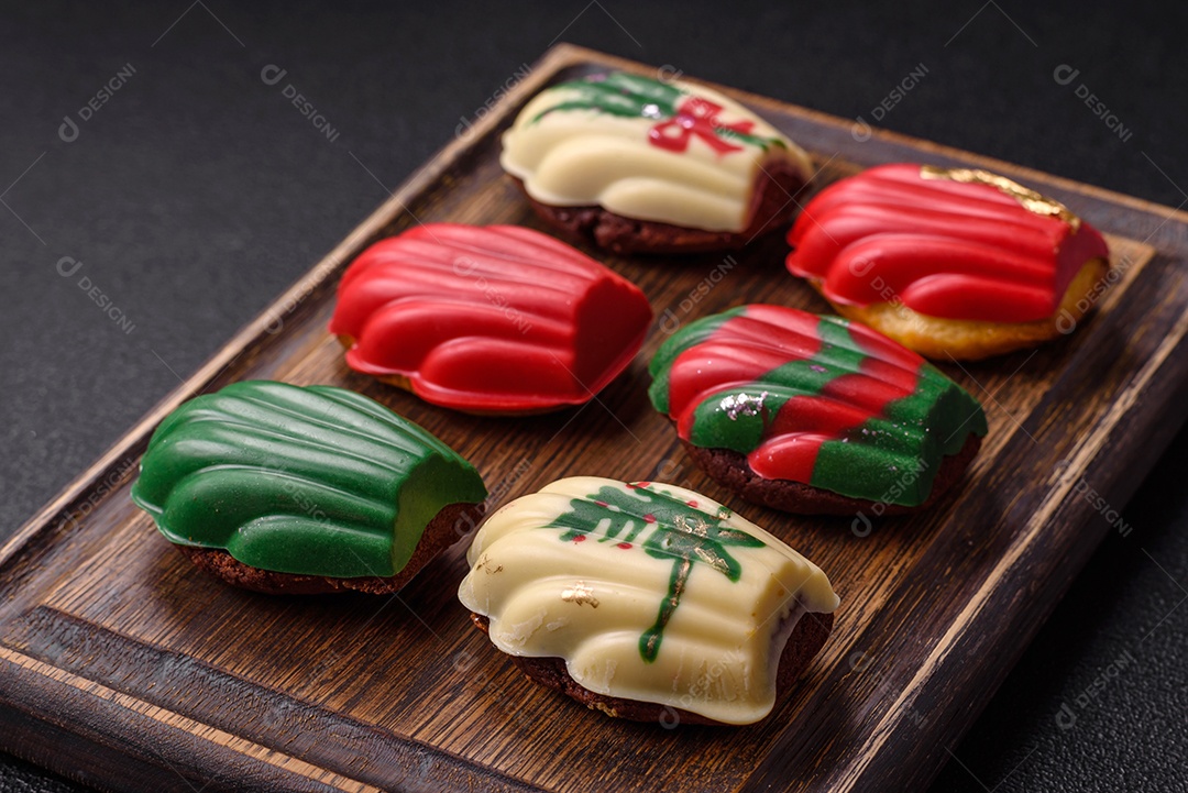 A imagem mostra uma caixa de madeira com biscoitos decorados com temas natalinos