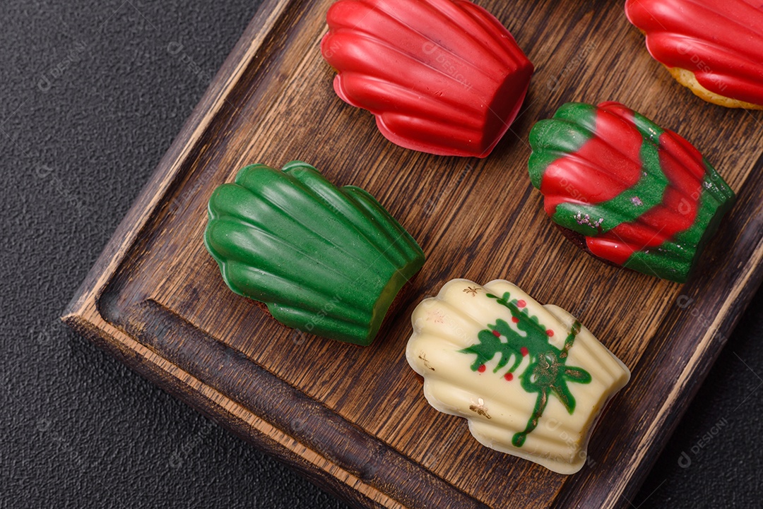 A imagem mostra uma caixa de madeira com biscoitos decorados com temas natalinos