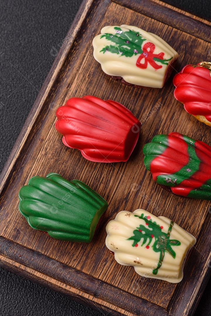 A imagem mostra uma caixa de madeira com biscoitos decorados com temas natalinos