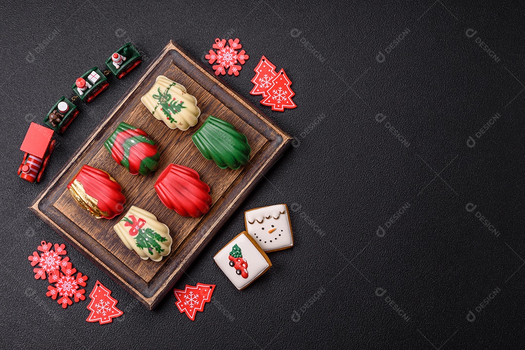 A imagem mostra uma caixa de madeira com biscoitos decorados com temas natalinos