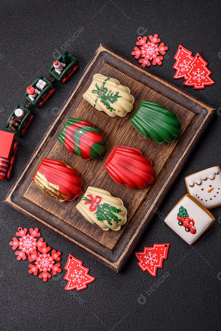 A imagem mostra uma caixa de madeira com biscoitos decorados com temas natalinos