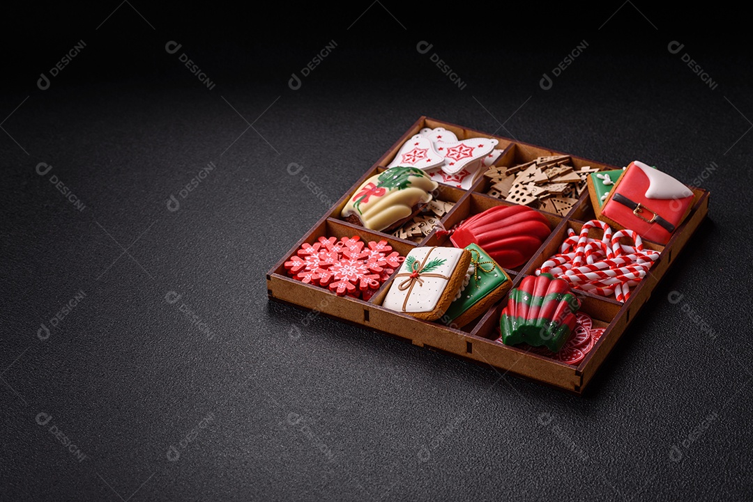 A imagem mostra uma caixa de madeira com biscoitos decorados com temas natalinos