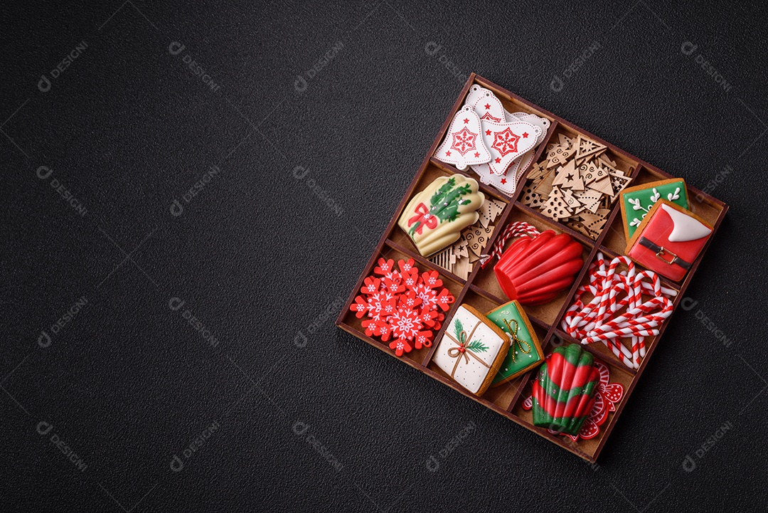 A imagem mostra uma caixa de madeira com biscoitos decorados com temas natalinos