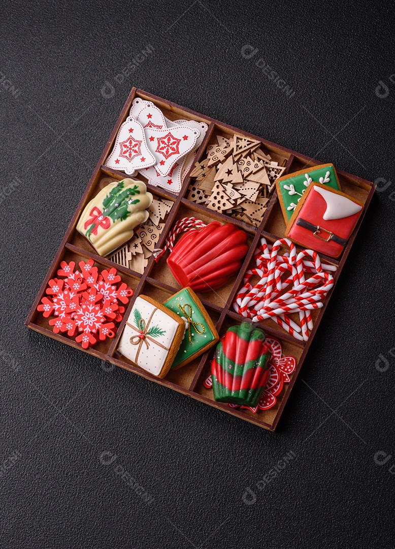 A imagem mostra uma caixa de madeira com biscoitos decorados com temas natalinos