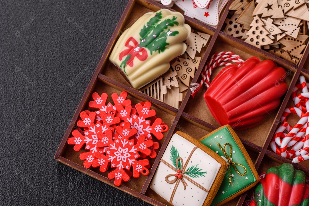 A imagem mostra uma caixa de madeira com biscoitos decorados com temas natalinos
