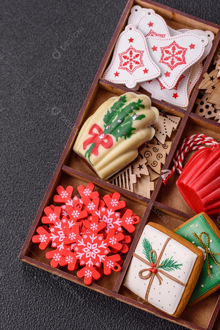 A imagem mostra uma caixa de madeira com biscoitos decorados com temas natalinos