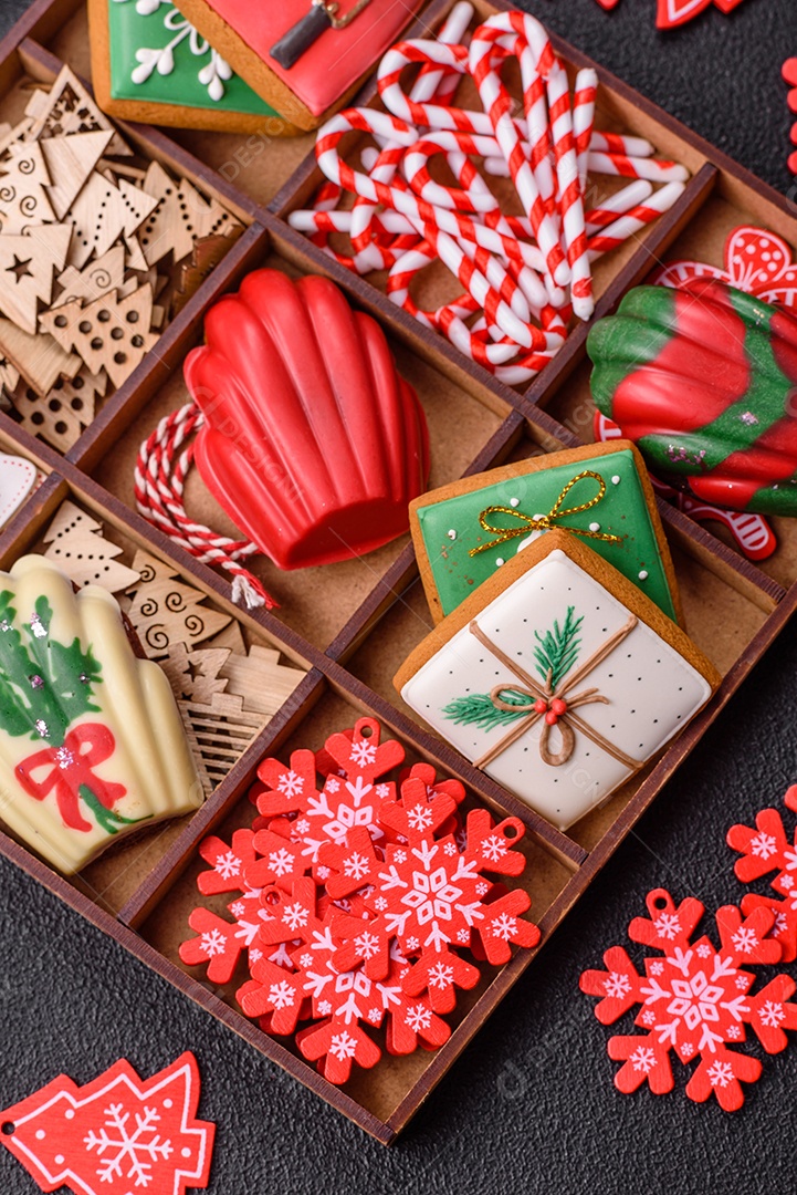 A imagem mostra uma caixa de madeira com biscoitos decorados com temas natalinos