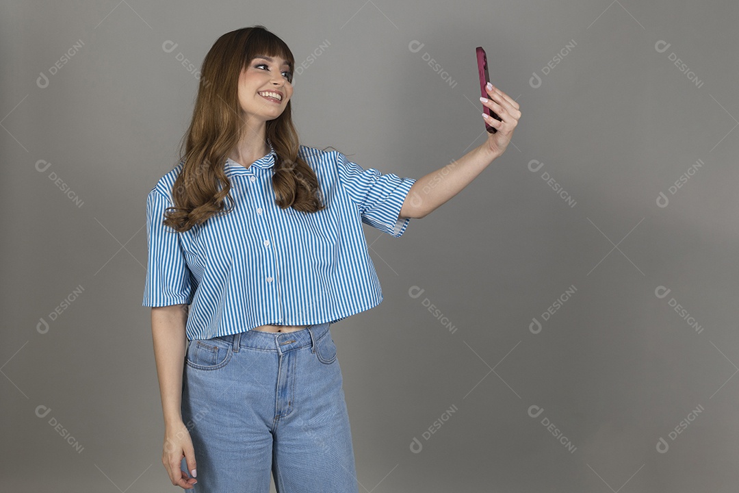 Linda mulher jovem sobre fundo isolado mexendo em seu celular smartphone