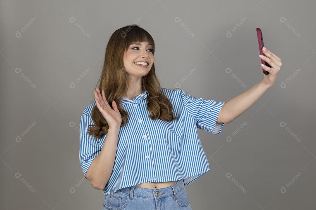 Linda mulher jovem sobre fundo isolado mexendo em seu celular smartphone