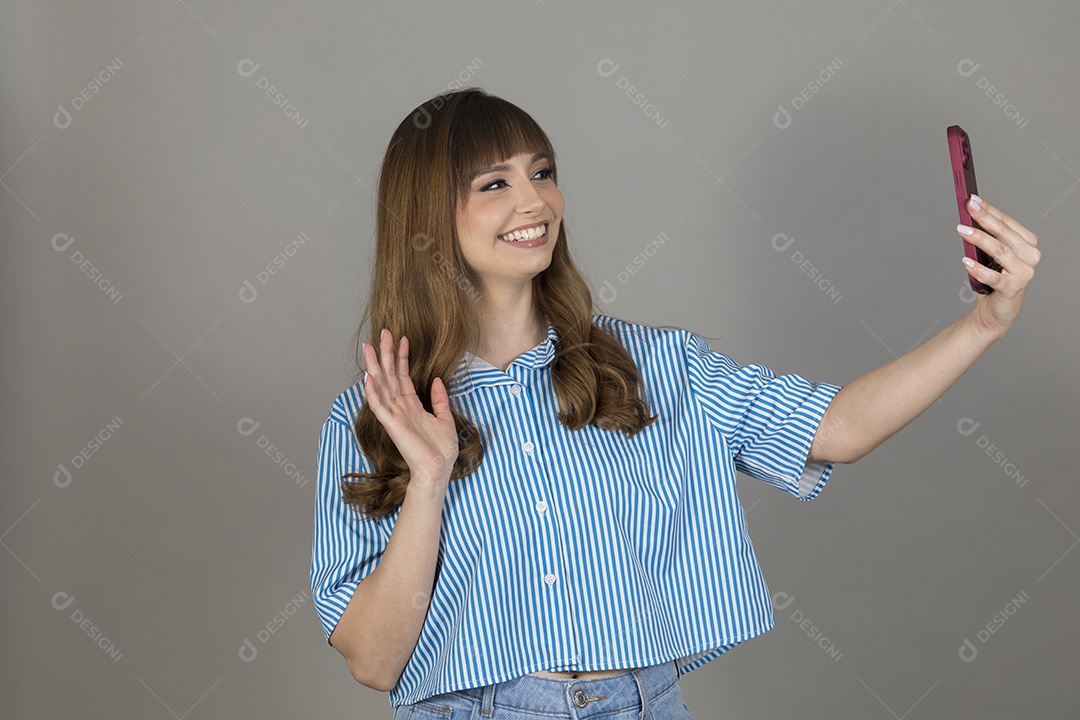 Linda mulher jovem sobre fundo isolado mexendo em seu celular smartphone