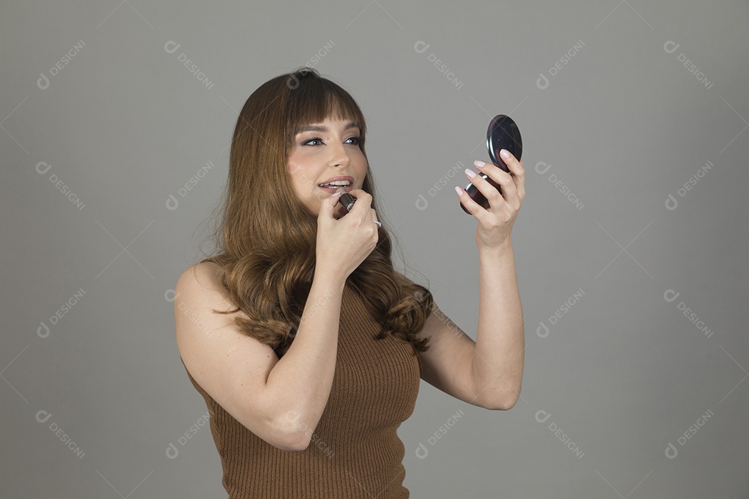 Linda mulher jovem se maquiando sobre fundo isolado branco