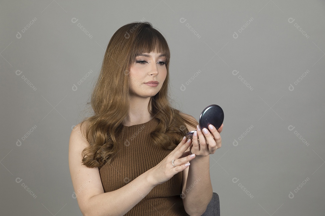 Linda mulher jovem se maquiando sobre fundo isolado branco