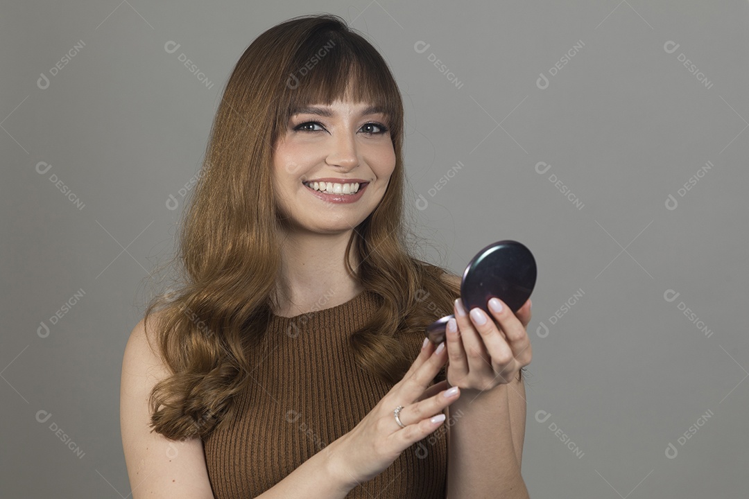 Linda mulher jovem se maquiando sobre fundo isolado branco