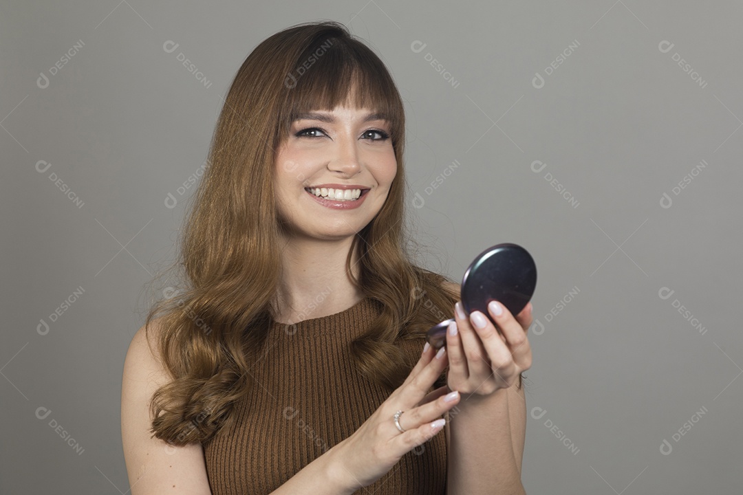 Linda mulher jovem se maquiando sobre fundo isolado branco