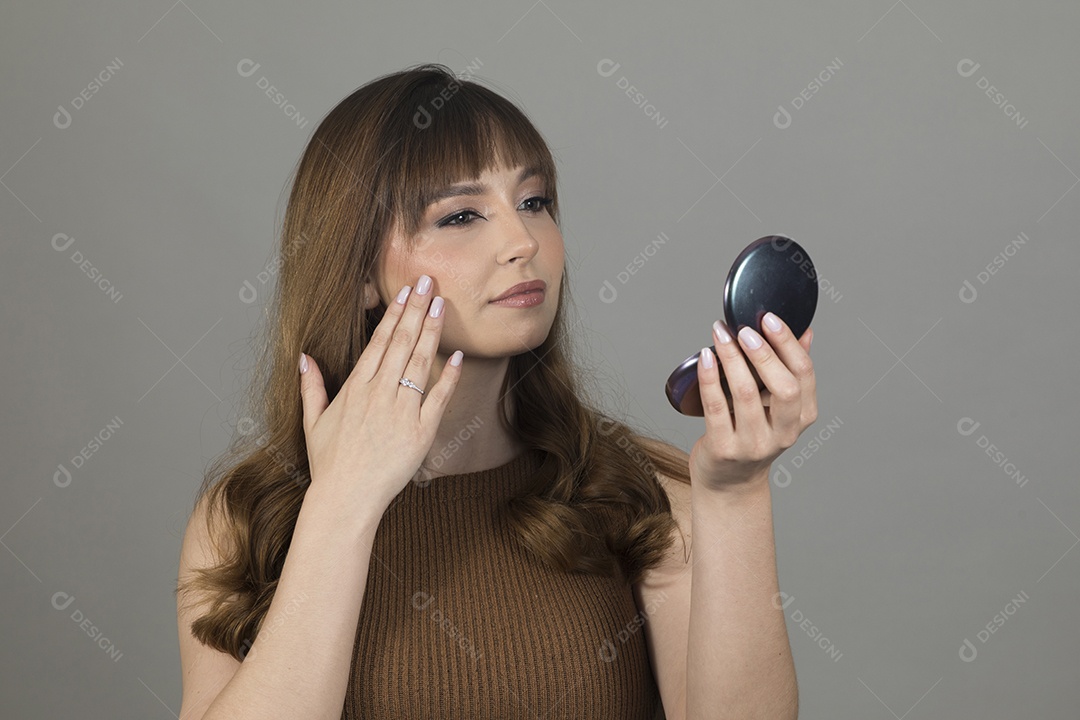Linda mulher jovem se maquiando sobre fundo isolado branco