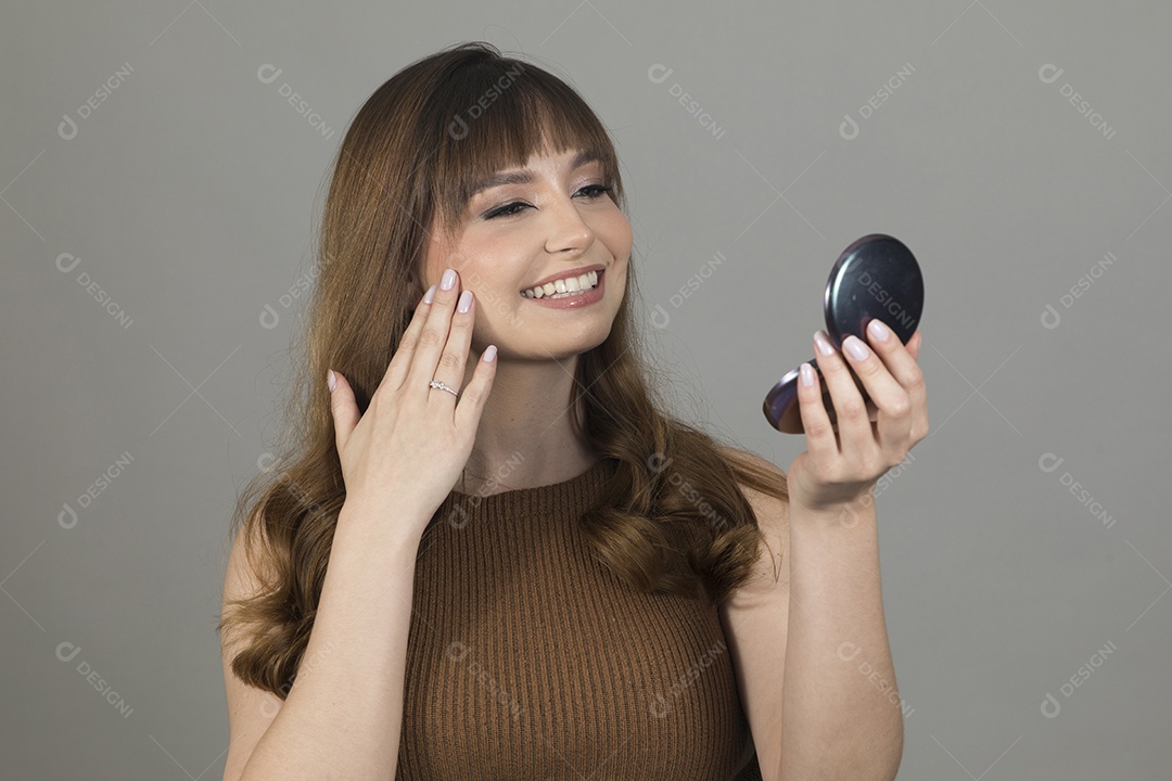 Linda mulher jovem se maquiando sobre fundo isolado branco