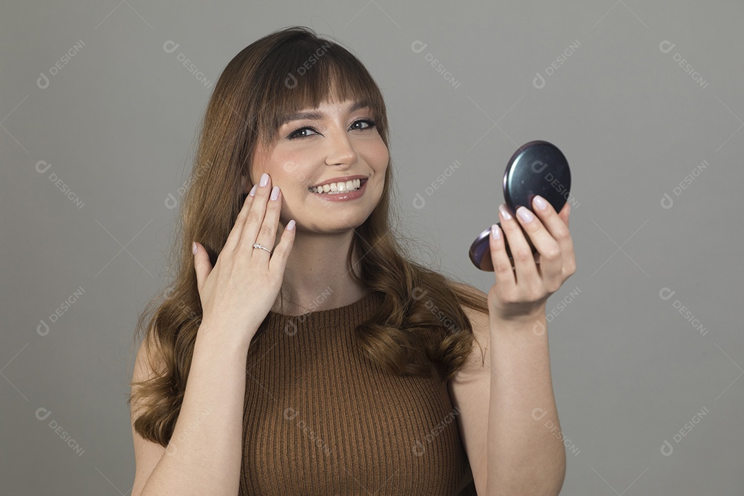 Linda mulher jovem se maquiando sobre fundo isolado branco