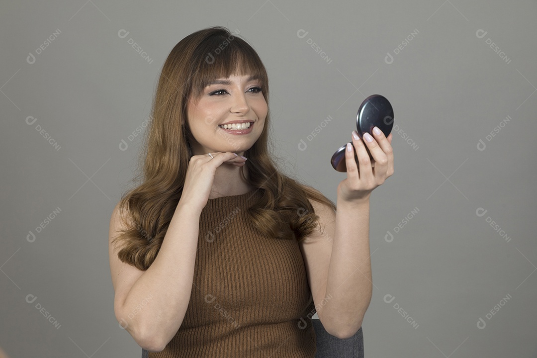 Linda mulher jovem se maquiando sobre fundo isolado branco
