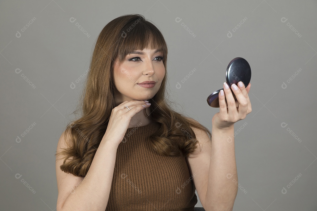 Linda mulher jovem se maquiando sobre fundo isolado branco