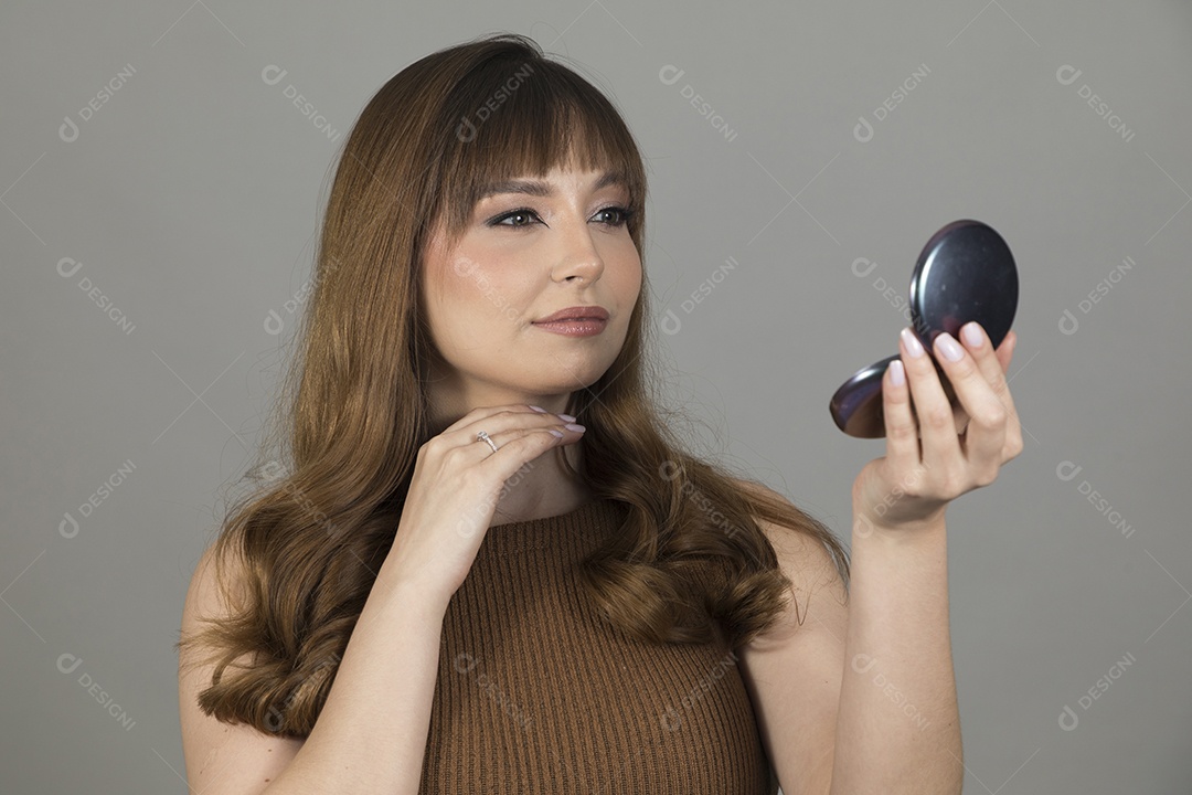 Linda mulher jovem se maquiando sobre fundo isolado branco
