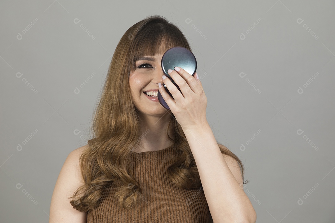 Linda mulher jovem se maquiando sobre fundo isolado branco