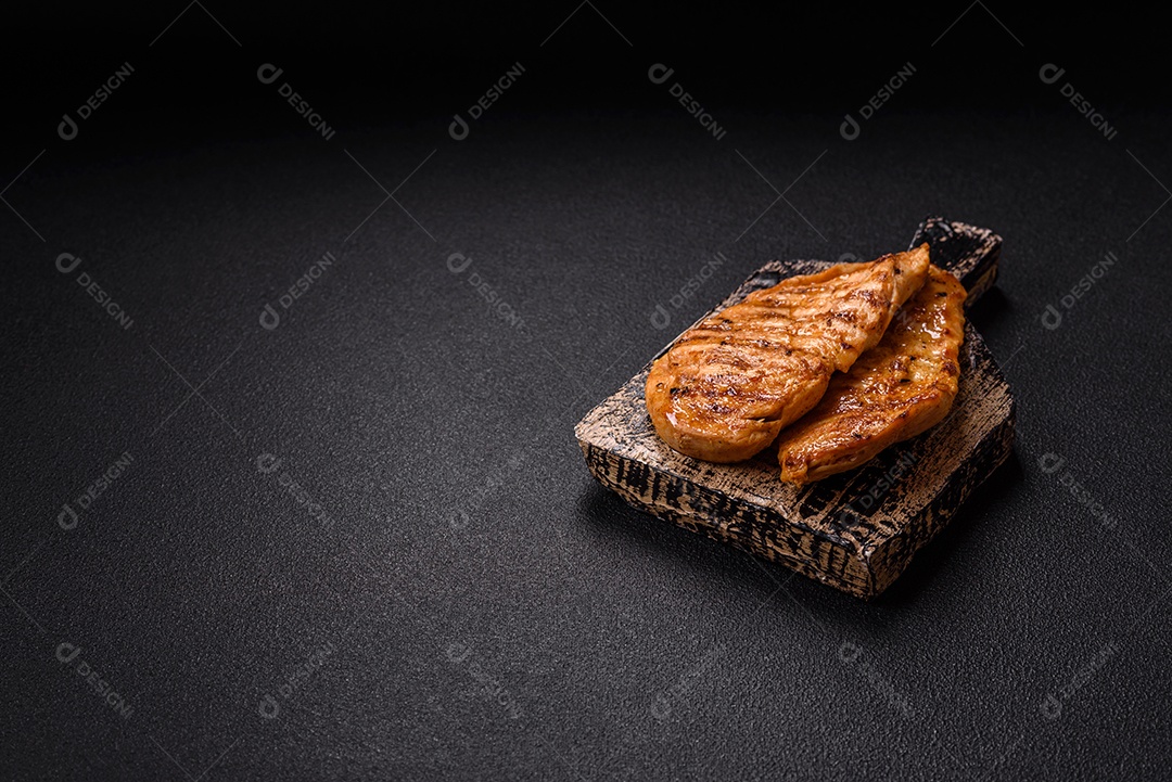 A imagem mostra filés de frango grelhados, acompanhados de temperos e tomates cereja.