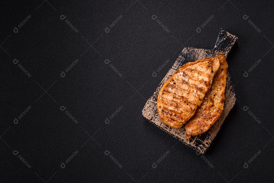 A imagem mostra filés de frango grelhados, acompanhados de temperos e tomates cereja.