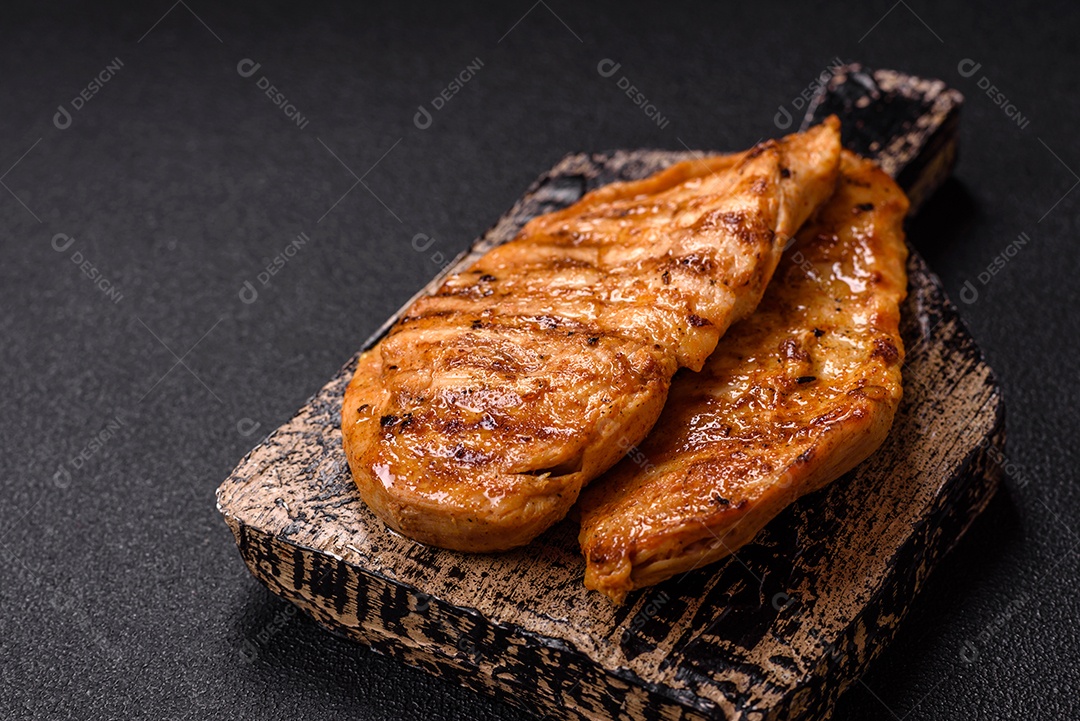 A imagem mostra filés de frango grelhados, acompanhados de temperos e tomates cereja.